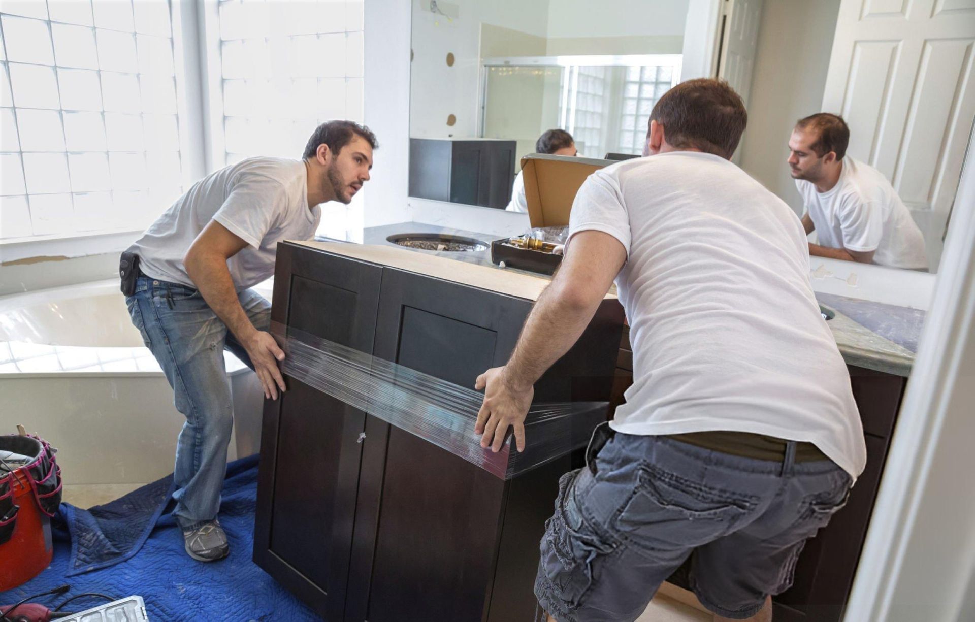 Two men carefully assemble a bathroom cabinet as part of a bathroom remodeling services project. Two men carefully assemble a bathroom cabinet as part of a bathroom remodeling services project.