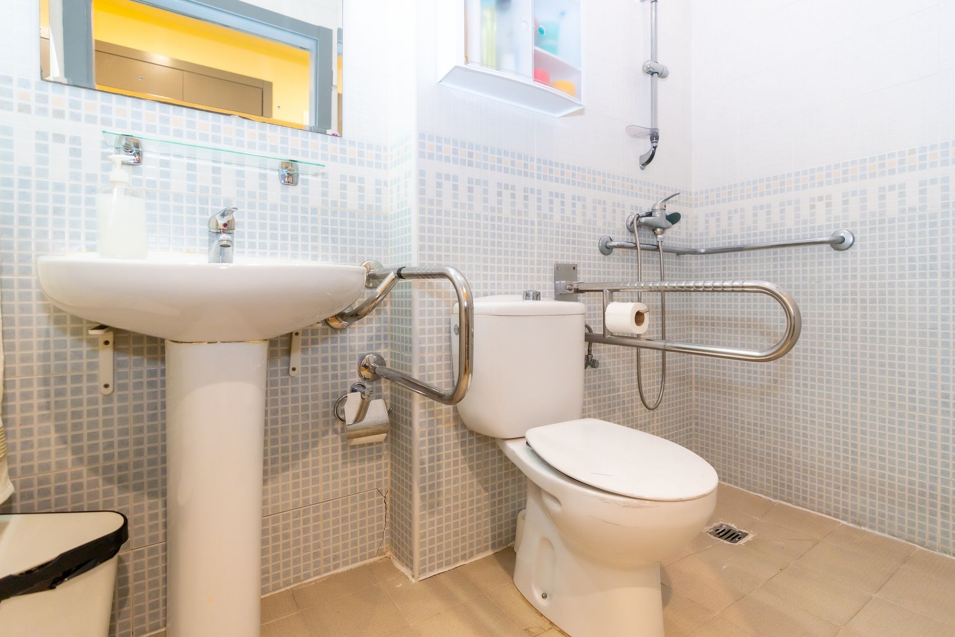 A bathroom with a toilet, sink and mirror.