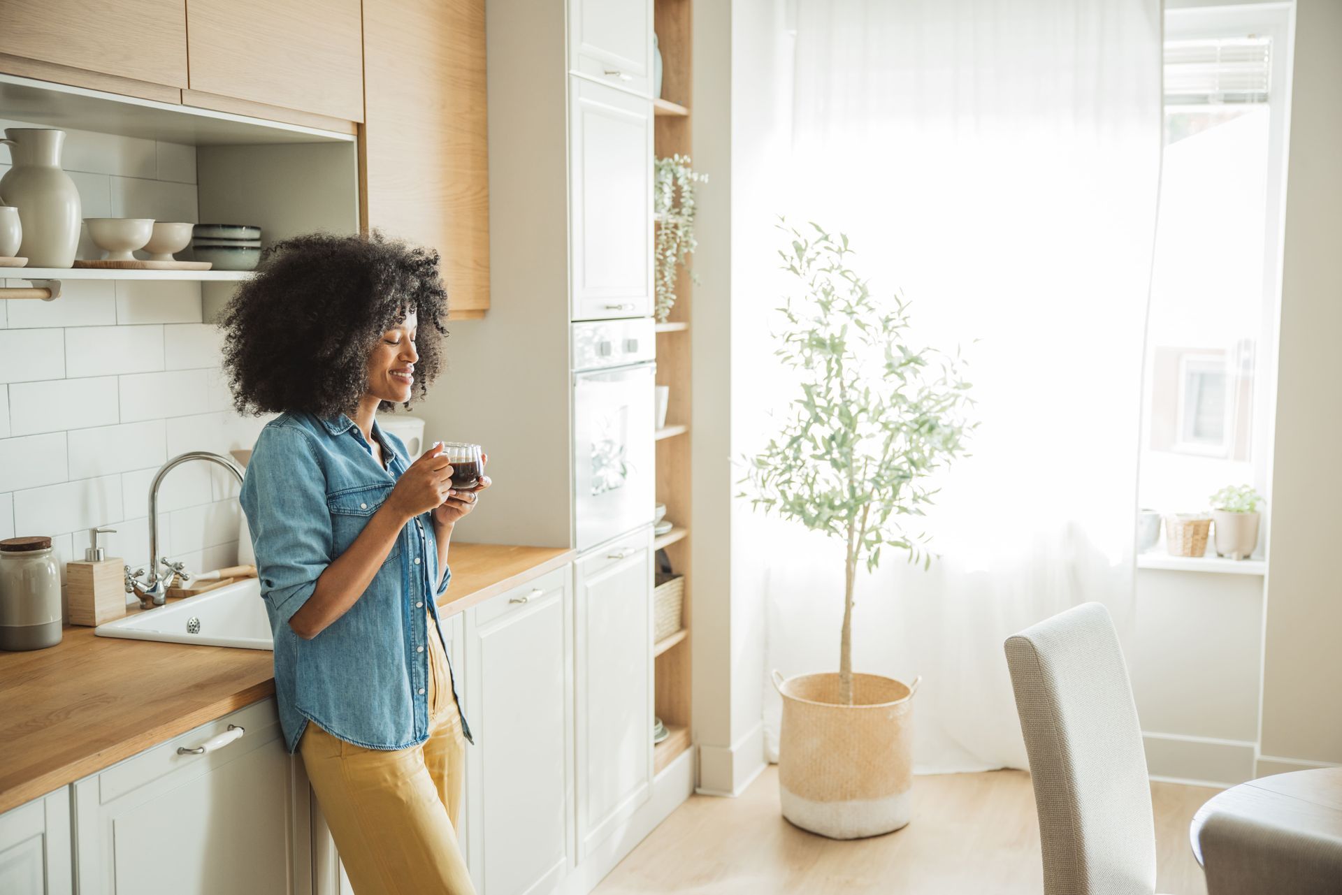 A happy woman with a coffee mug enjoying her morning in her remodeled home kitchen.