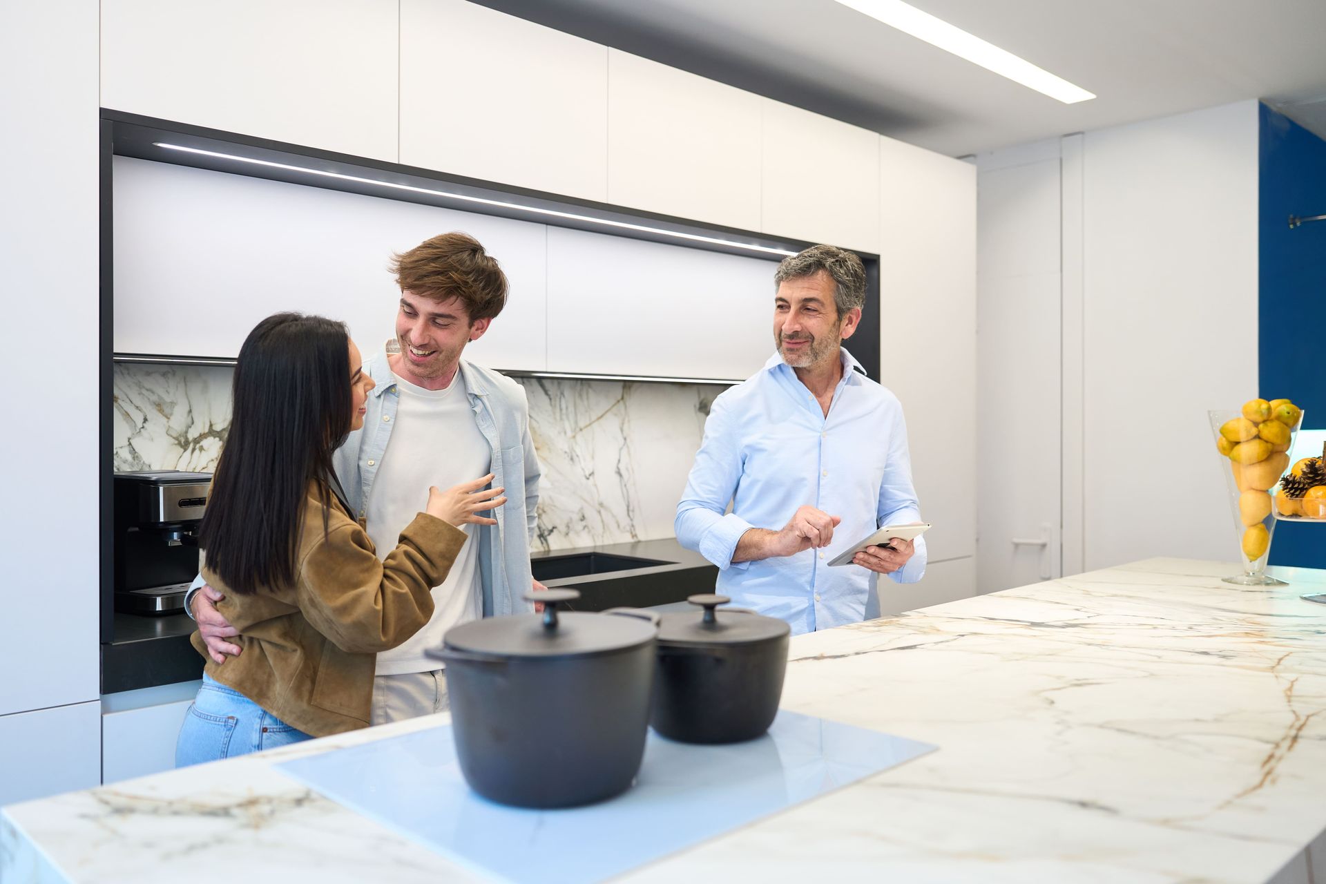 A couple discussing kitchen design with an interior designer who is using a tablet.