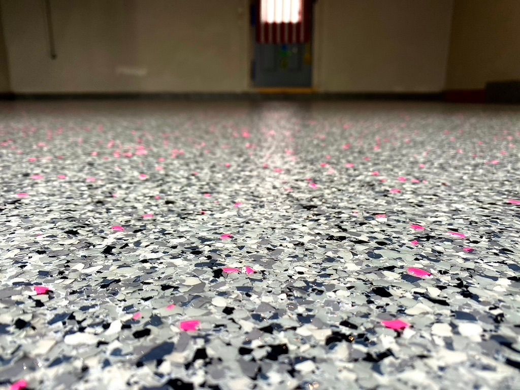 Woman in straw hat smiles, holding wine glass near a lake.