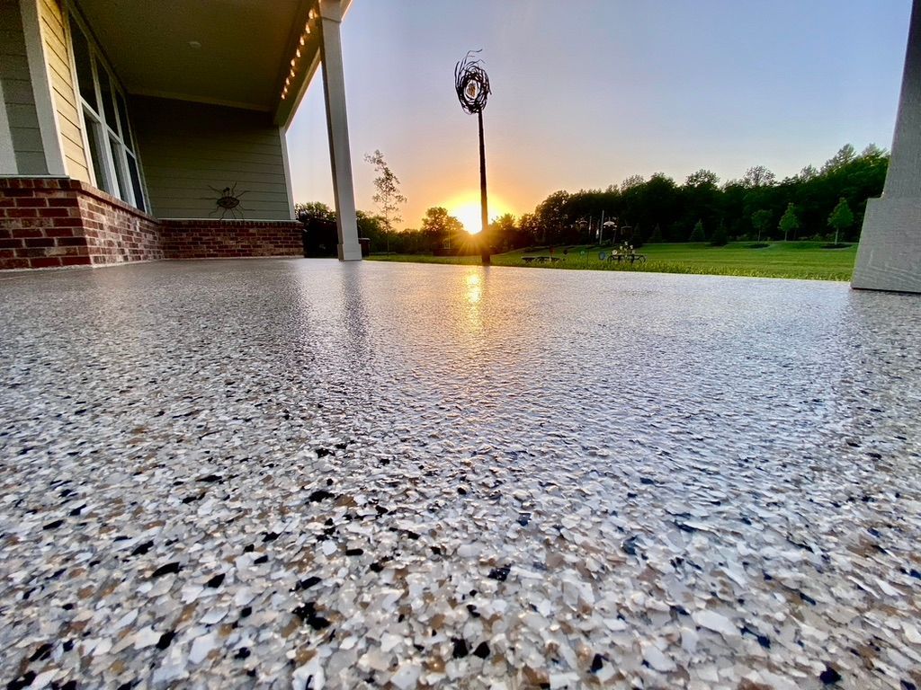 Woman in straw hat smiles, holding wine glass near a lake.