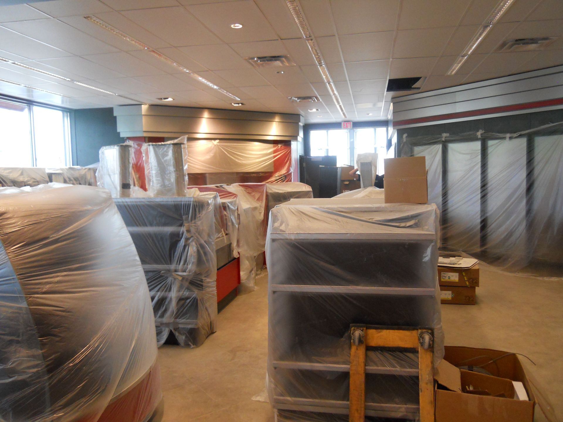Modern conference room with long wooden table, black chairs, projector screen, and large windows.