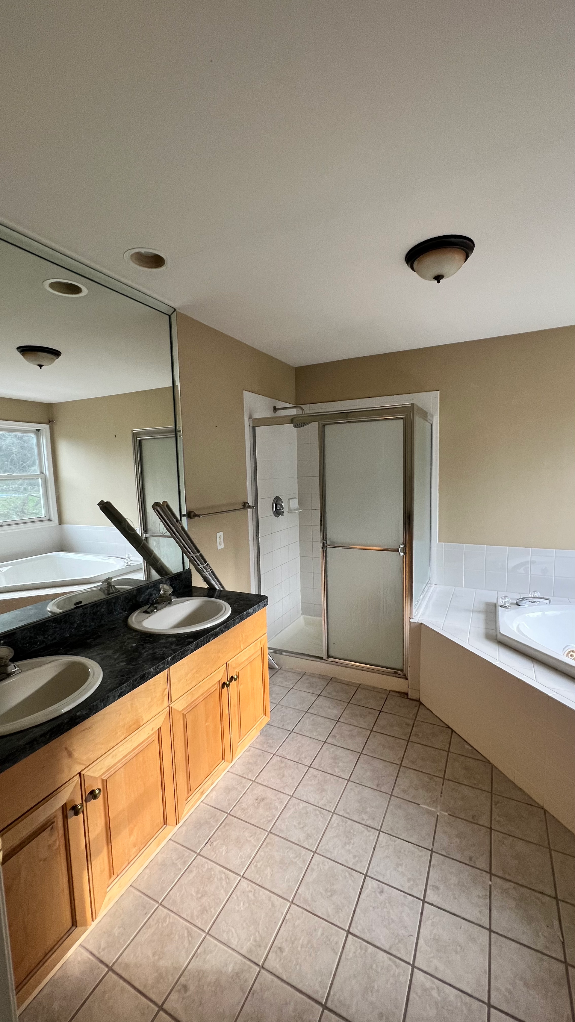 A bathroom with two sinks , a tub , and a walk in shower.