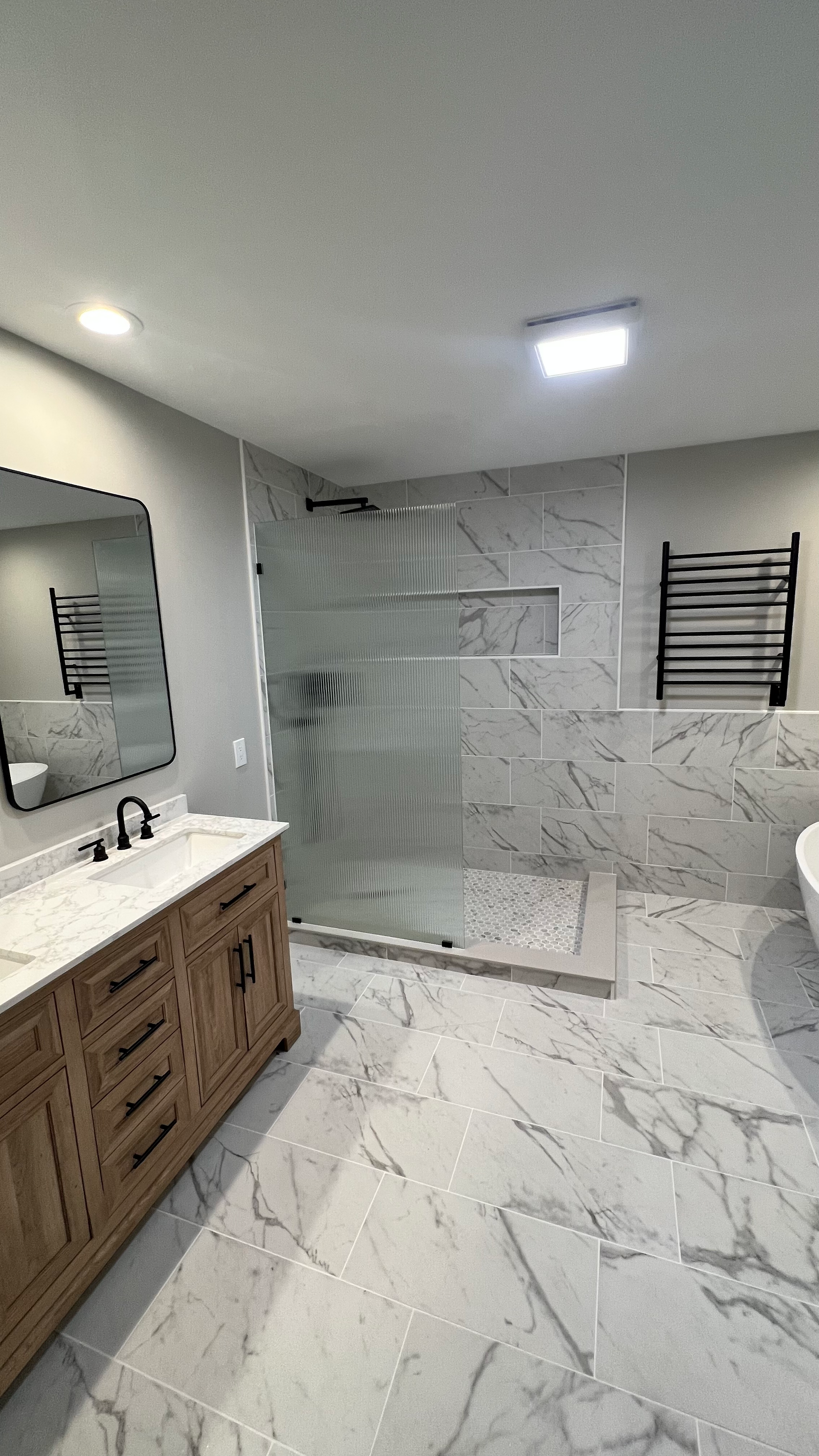 A bathroom with a walk in shower , sink and mirror.