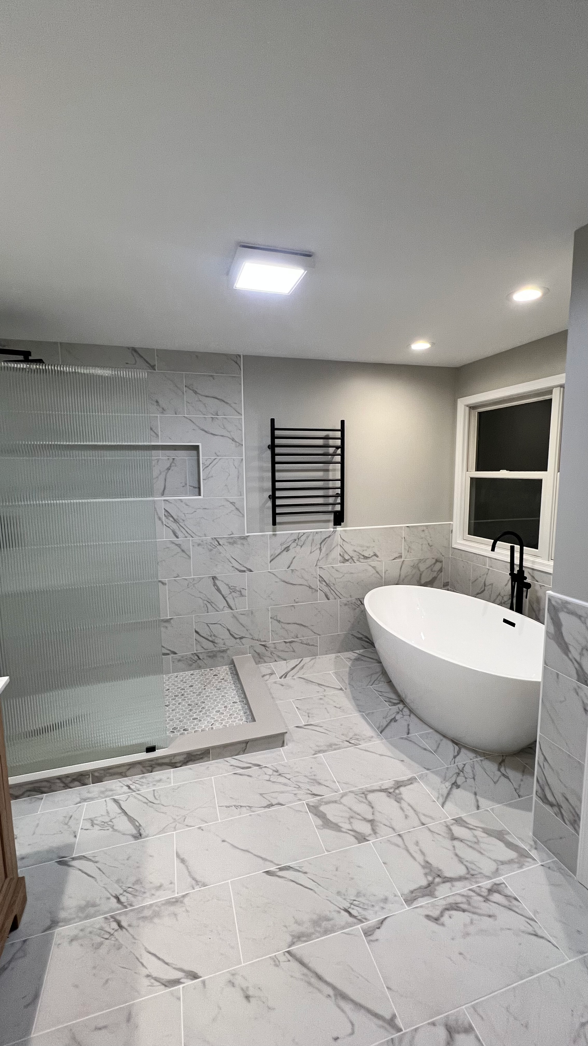 A bathroom with a tub , shower , and window.