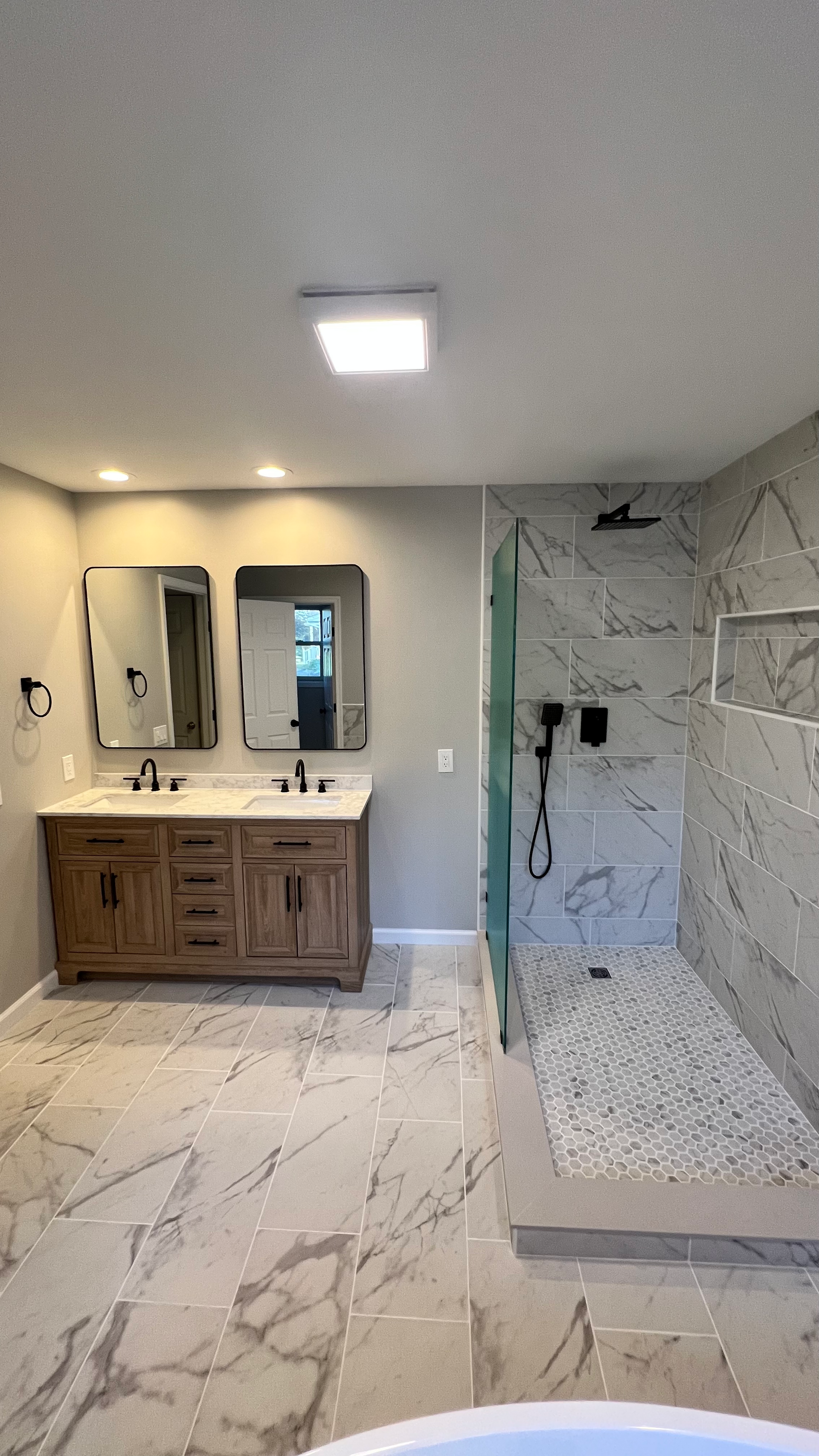 A bathroom with two sinks and a walk in shower.