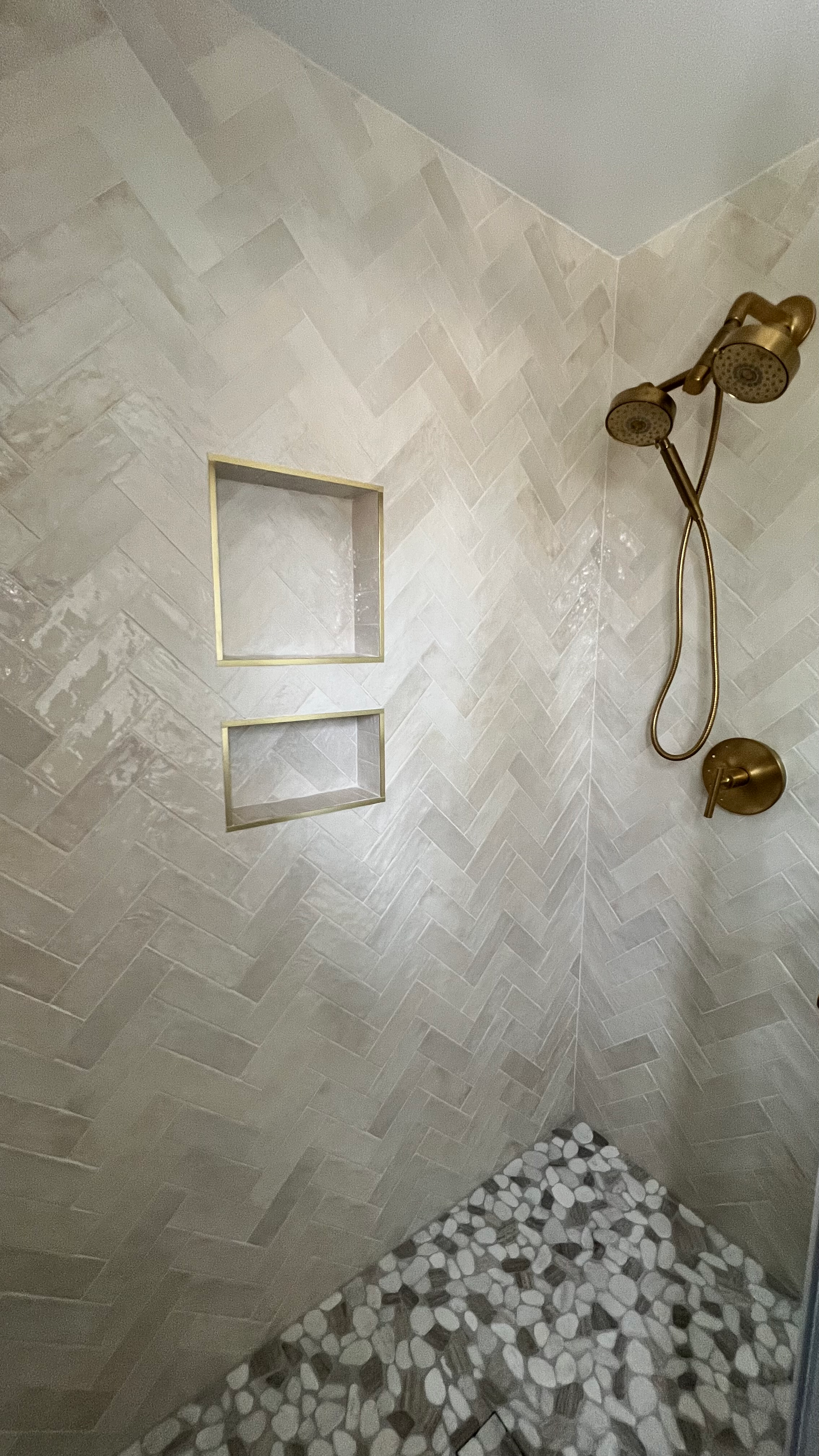A shower with a shower head and two shelves on the wall.