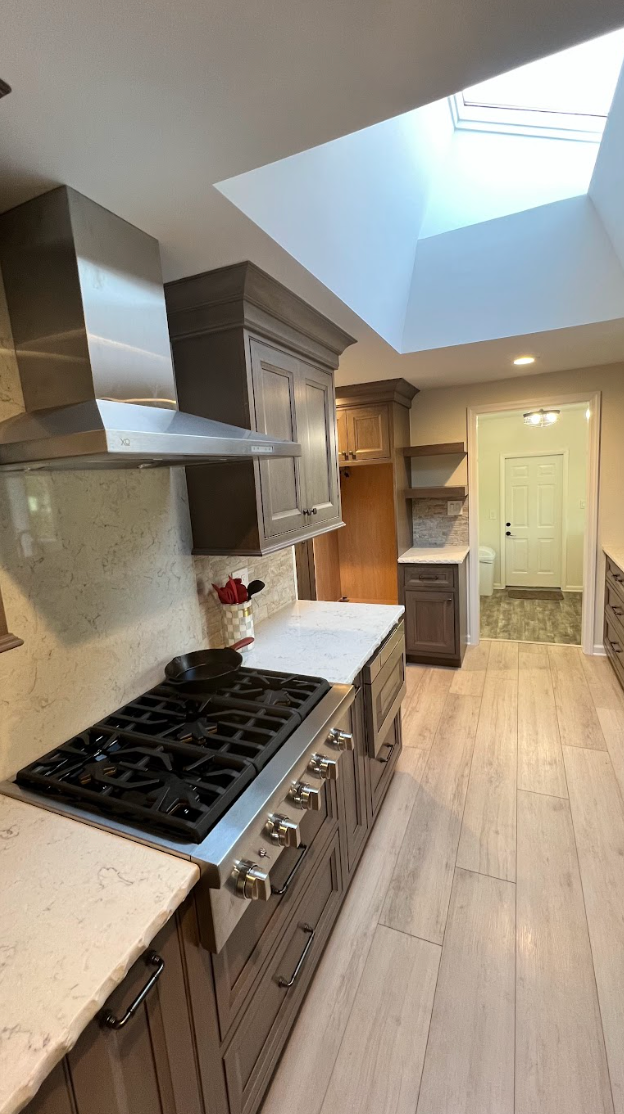 A kitchen with a stove top oven and a skylight.
