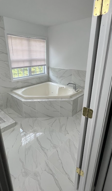 A bathroom with a jacuzzi tub and a window.