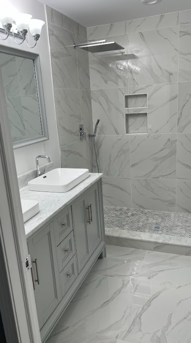 A bathroom with a sink , mirror , and walk in shower.