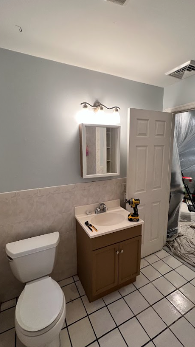 A bathroom with a toilet , sink and mirror.