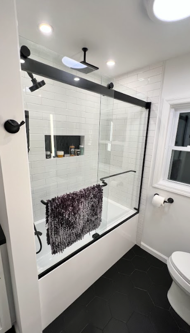 A bathroom with a bathtub , toilet , shower and skylight.