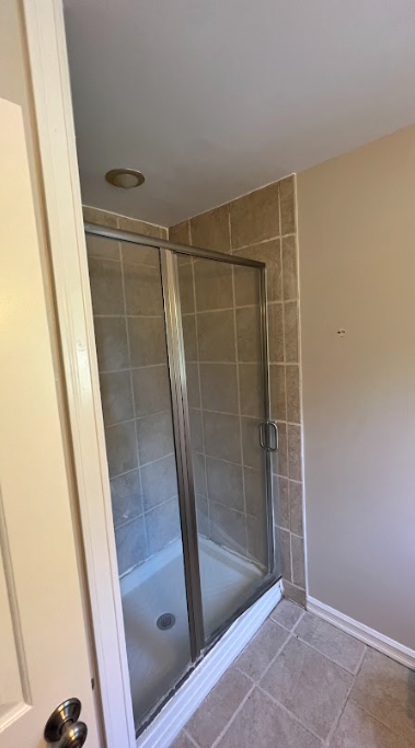 A bathroom with a walk in shower with a glass door.