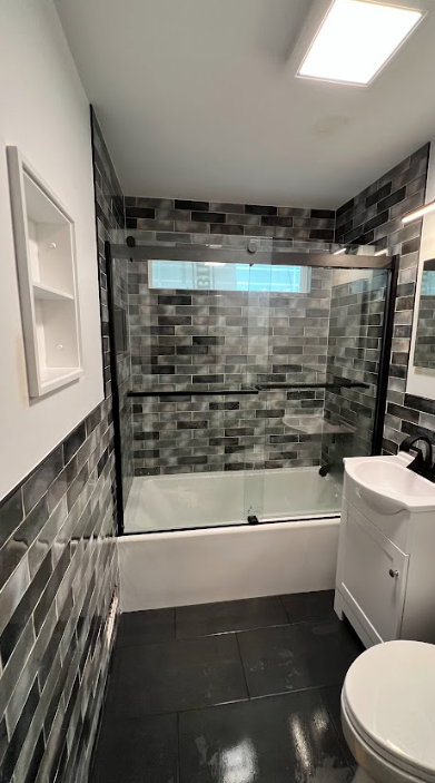 A bathroom with a toilet , sink , bathtub and shower.