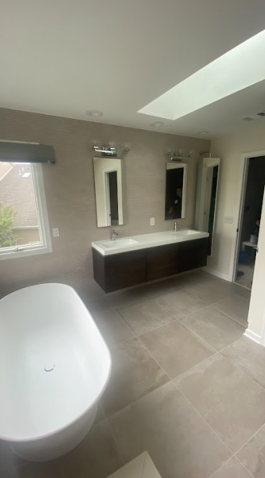 A bathroom with a tub , sink and mirrors.