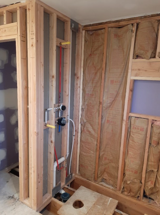 A bathroom is being built with wooden frames and insulation.