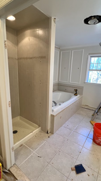 A bathroom with a tub , shower , and window.