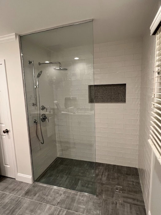 A bathroom with a walk in shower with a glass door.