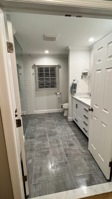 A bathroom with a toilet , sink , and window.