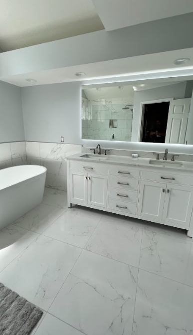 A bathroom with two sinks , a tub , and a large mirror.