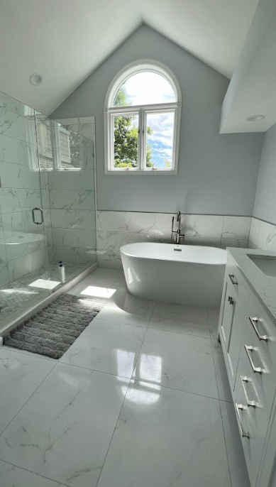 A bathroom with a tub , shower and window.