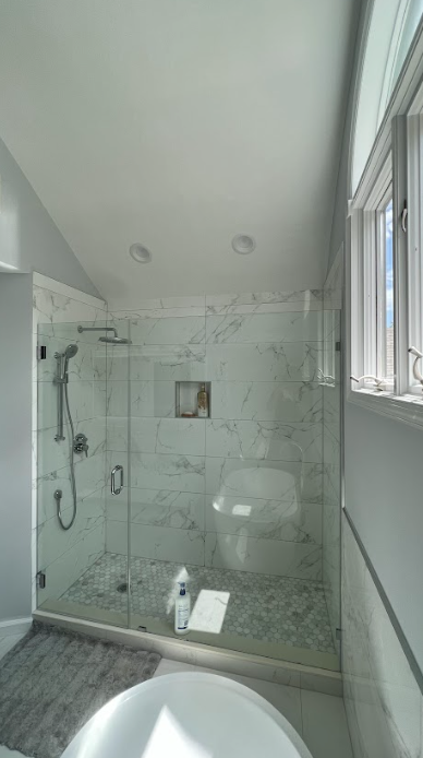 A bathroom with a tub , shower , and window.