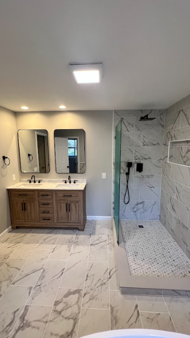 A bathroom with two sinks and a walk in shower.