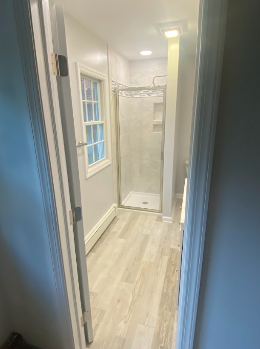 A bathroom with a walk in shower and a window.