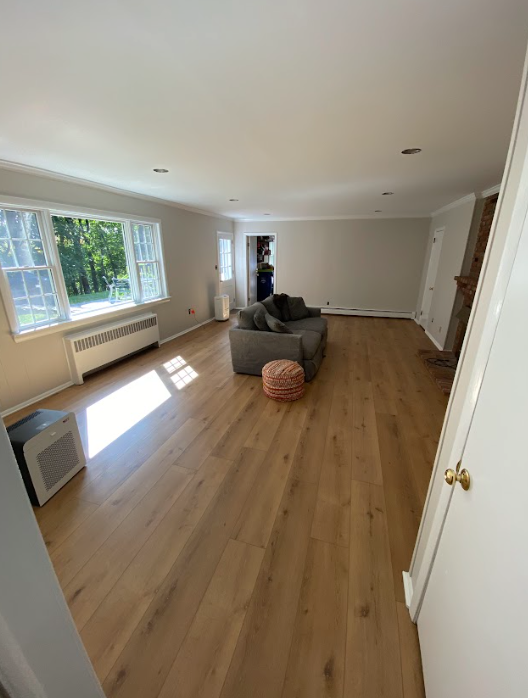 A living room with hardwood floors , a couch , and a window.