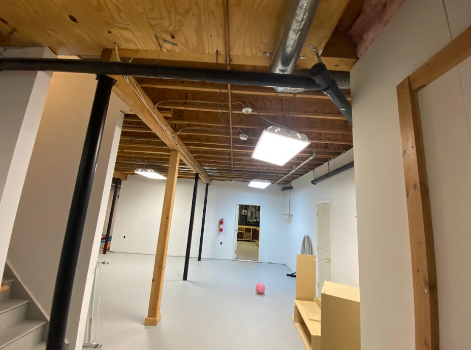 An empty basement with a wooden ceiling and stairs
