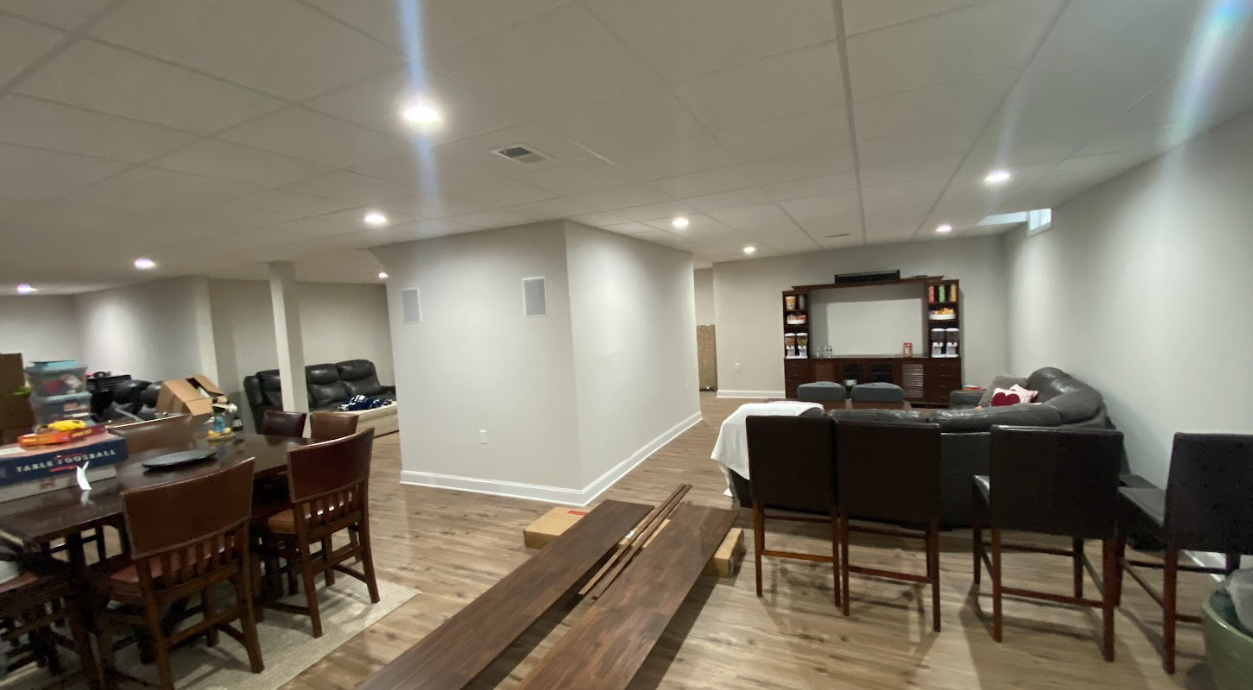 A living room with a couch , chairs , a table and a projector screen.