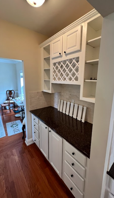 A kitchen with white cabinets and a wine rack above the counter.