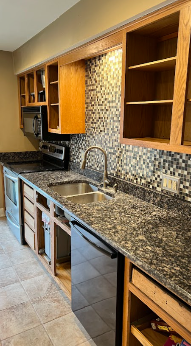 A kitchen with granite counter tops , stainless steel appliances , and wooden cabinets.
