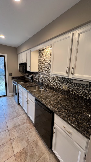 A kitchen with granite counter tops and white cabinets.