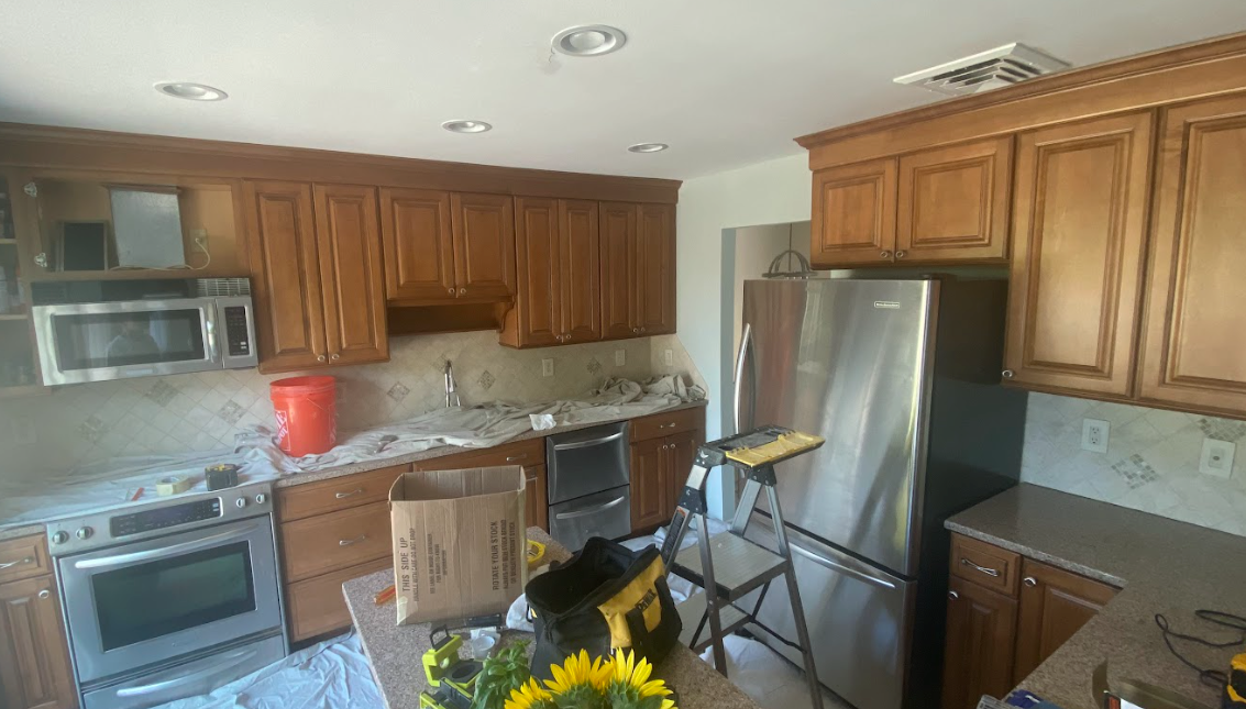 A kitchen with stainless steel appliances and wooden cabinets is being remodeled.