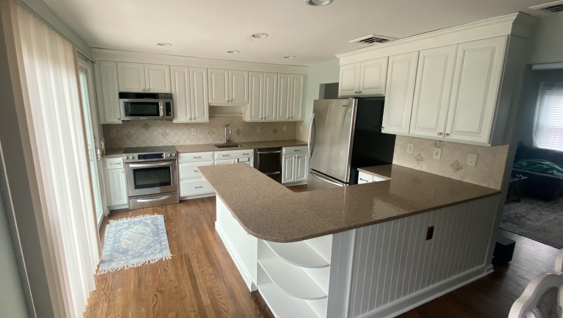 A kitchen with white cabinets , granite counter tops , stainless steel appliances and a large island.