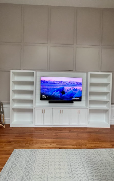 A living room with a white entertainment center and a flat screen tv.