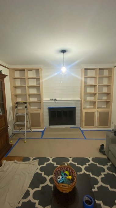A living room with a fireplace and a basket of toys on the floor.