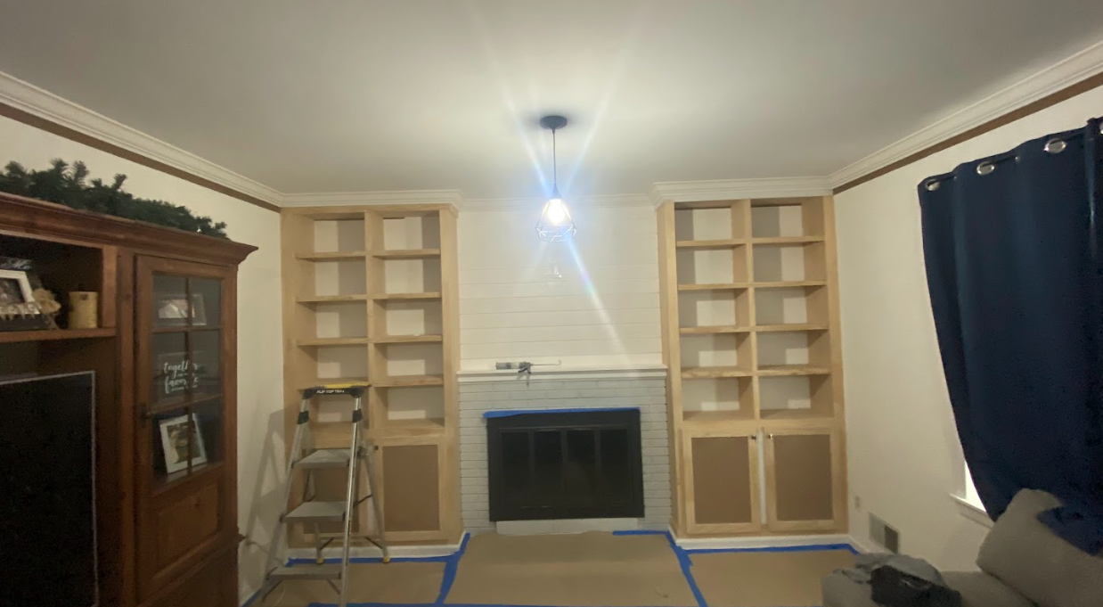 A living room with a fireplace , shelves and a ladder.