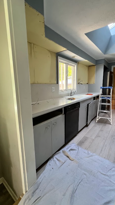 A kitchen with a sink , dishwasher , and ladder.