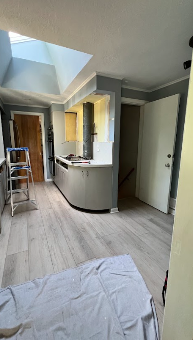 A kitchen with a skylight and a ladder in it.