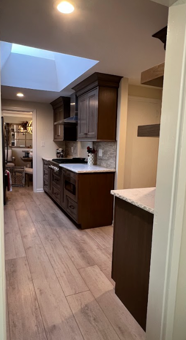 A kitchen with wooden floors and a skylight in the ceiling.