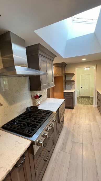 A kitchen with a stove top oven and a skylight.