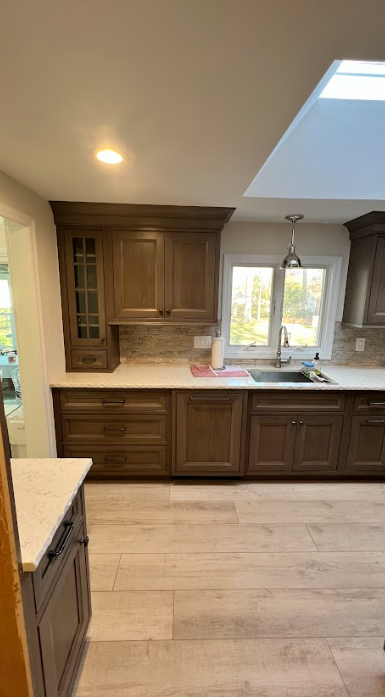 A kitchen with wooden cabinets , a sink , and a skylight.