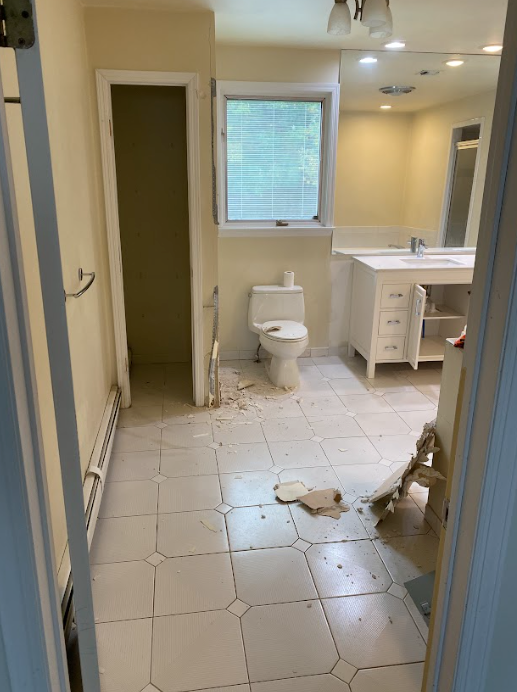 A bathroom with a toilet , sink and mirror.