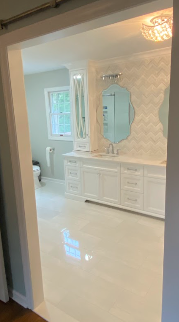 A bathroom with white cabinets and a large mirror.
