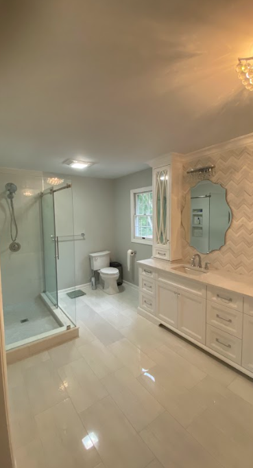 A bathroom with a toilet , sink , shower and mirror.