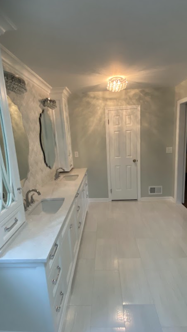 A bathroom with two sinks , two mirrors , and a door.