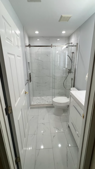 A bathroom with a toilet , sink and walk in shower.